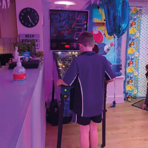 Kid playing a pinball machine in the home